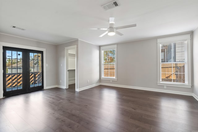 empty room with a healthy amount of sunlight, visible vents, and dark wood-type flooring