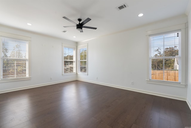 empty room featuring dark wood-style floors, visible vents, ceiling fan, and baseboards