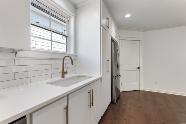 kitchen with light countertops, freestanding refrigerator, white cabinetry, and a sink