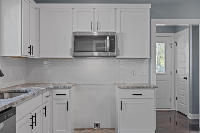 kitchen featuring a sink, white cabinets, appliances with stainless steel finishes, light stone countertops, and tasteful backsplash