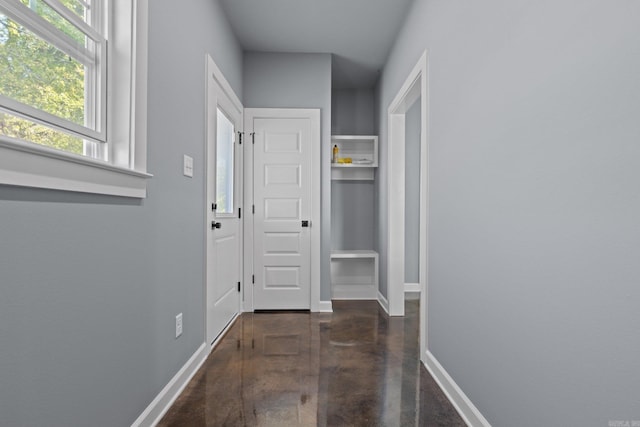 corridor with finished concrete floors and baseboards