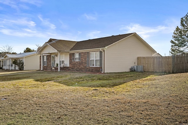 ranch-style house with a front yard, brick siding, fence, and central air condition unit