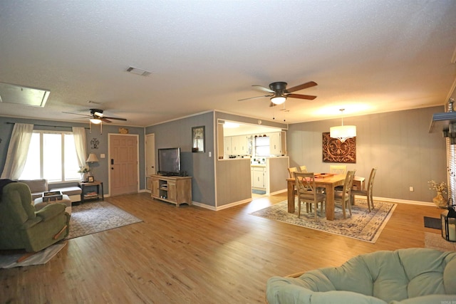 living room with baseboards, visible vents, ceiling fan, and light wood finished floors