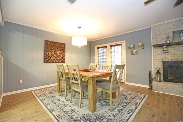 dining room with baseboards, a fireplace, wood finished floors, and crown molding