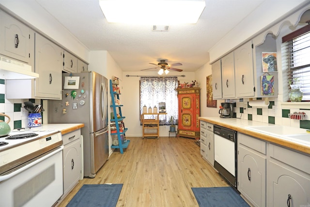 kitchen with light countertops, white appliances, a wealth of natural light, and under cabinet range hood