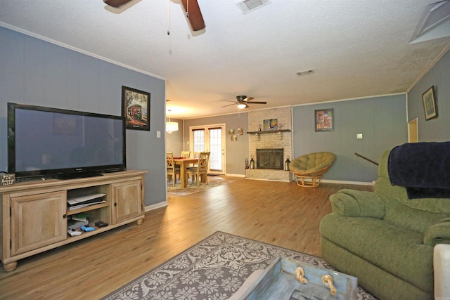 living room featuring ornamental molding, a brick fireplace, visible vents, and light wood-style flooring