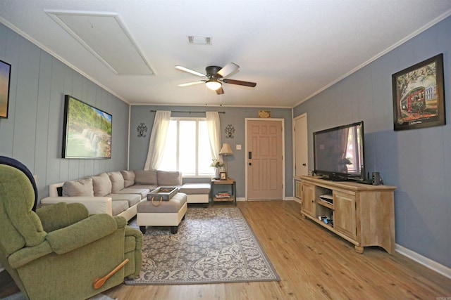 living area with attic access, light wood-type flooring, visible vents, and crown molding