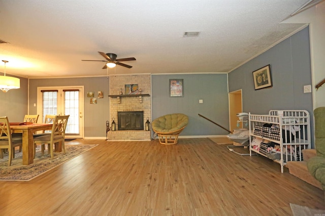 living room with a brick fireplace, baseboards, ornamental molding, and wood finished floors