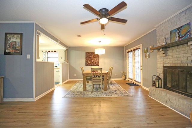 dining room with a fireplace, crown molding, baseboards, and wood finished floors