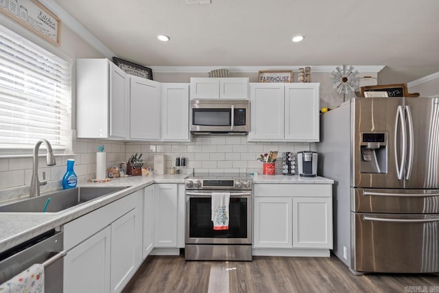 kitchen featuring light countertops, appliances with stainless steel finishes, ornamental molding, white cabinets, and a sink