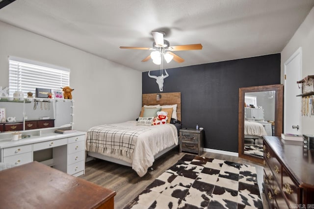 bedroom with wood finished floors, a ceiling fan, and baseboards