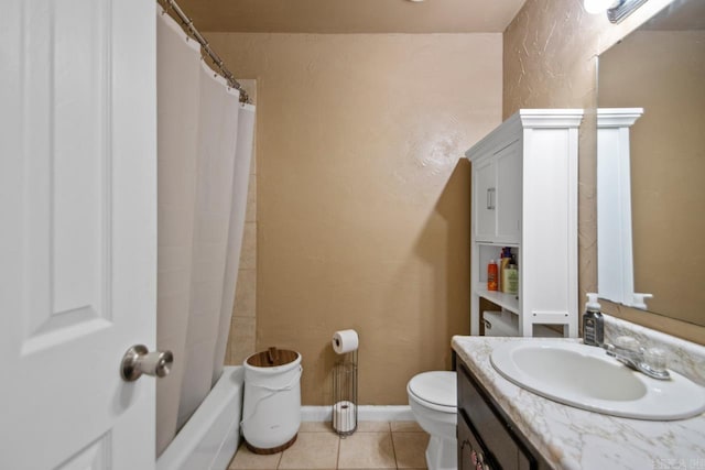 bathroom featuring a textured wall, toilet, vanity, baseboards, and tile patterned floors