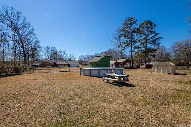 view of yard with a storage shed, fence, and an outdoor pool