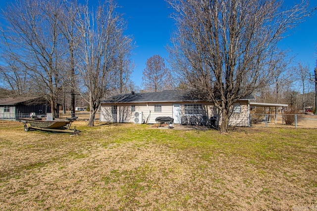 rear view of property with a carport, fence, and a lawn