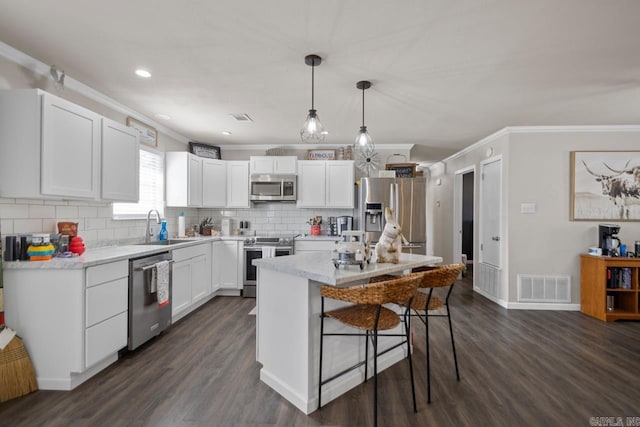 kitchen with a center island, stainless steel appliances, visible vents, white cabinetry, and a sink