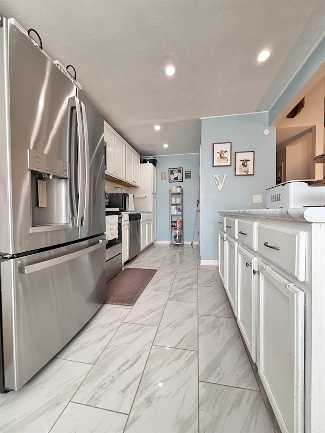 kitchen featuring recessed lighting, white cabinetry, baseboards, marble finish floor, and appliances with stainless steel finishes