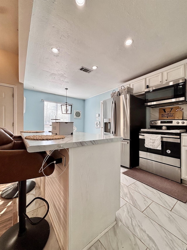 kitchen with marble finish floor, visible vents, hanging light fixtures, appliances with stainless steel finishes, and white cabinetry