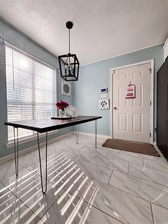 unfurnished dining area with marble finish floor, a textured ceiling, baseboards, and an inviting chandelier