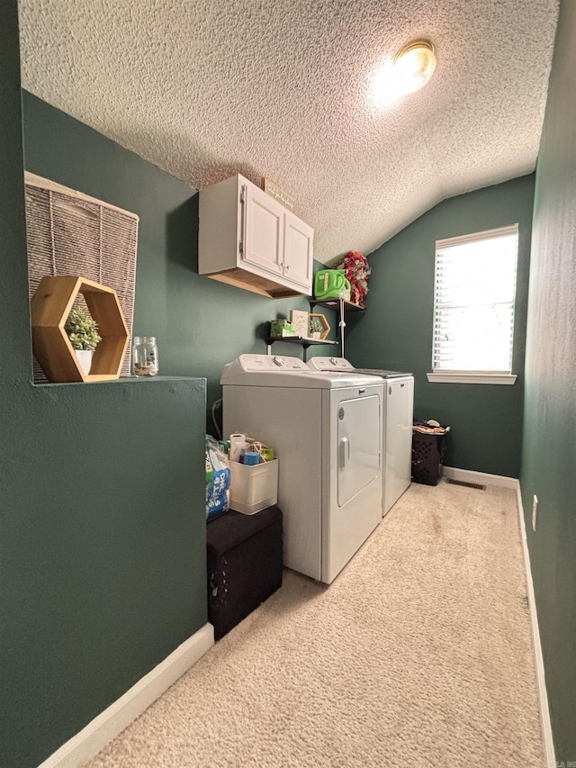 laundry area featuring light colored carpet, cabinet space, independent washer and dryer, and a textured ceiling