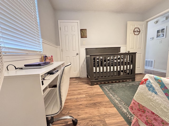 bedroom with visible vents, a textured ceiling, and light wood finished floors