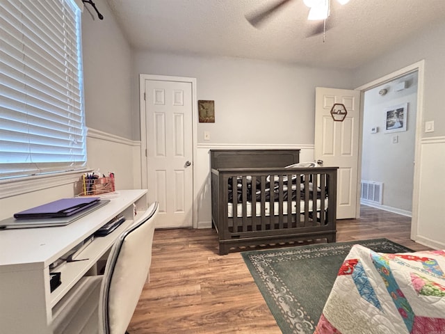 bedroom with visible vents, ceiling fan, a textured ceiling, and wood finished floors