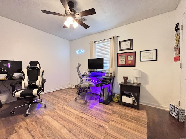 office featuring a ceiling fan, light wood-type flooring, visible vents, and baseboards