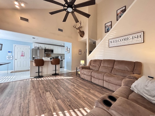 living area with ceiling fan, wood finished floors, visible vents, and baseboards