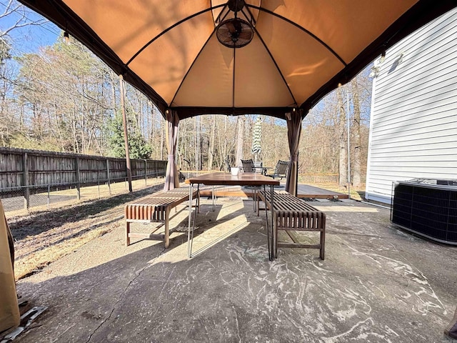 view of patio featuring a fenced backyard, outdoor dining area, cooling unit, and a gazebo