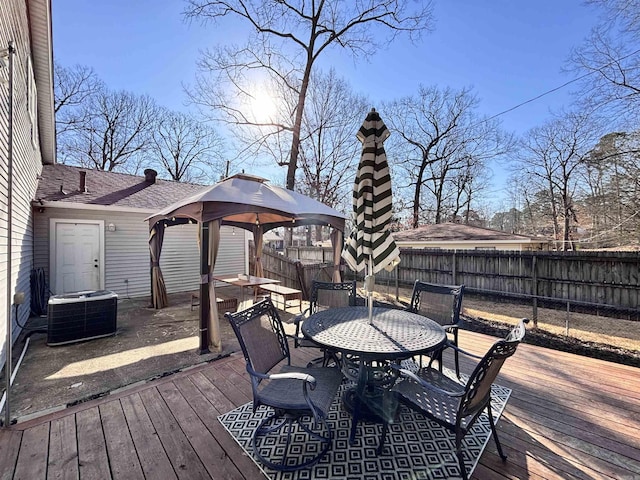 wooden deck with outdoor dining space, central AC, a fenced backyard, and a gazebo