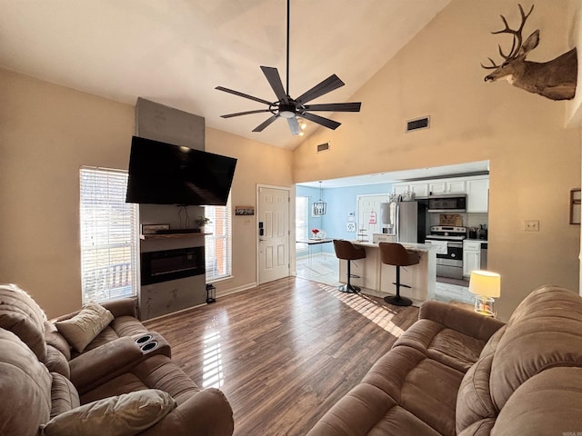 living area featuring ceiling fan, a large fireplace, wood finished floors, and visible vents