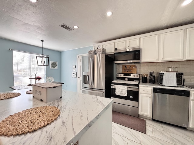 kitchen with decorative light fixtures, stainless steel appliances, visible vents, backsplash, and white cabinetry