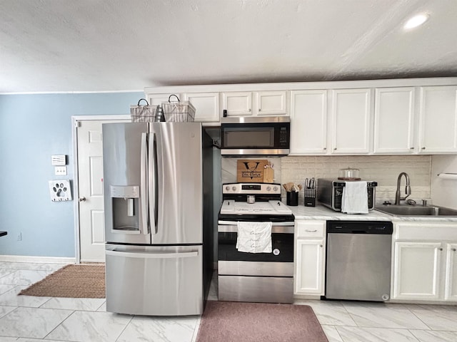 kitchen with marble finish floor, stainless steel appliances, light countertops, white cabinetry, and a sink