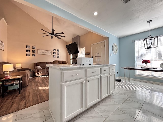 kitchen with open floor plan, marble finish floor, hanging light fixtures, and white cabinetry