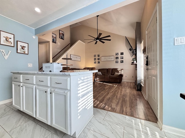 kitchen featuring marble finish floor, white cabinets, light countertops, and open floor plan