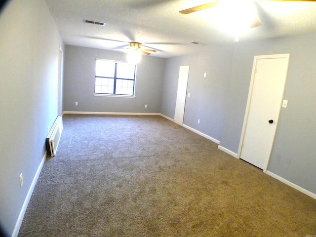 carpeted empty room featuring visible vents, ceiling fan, a textured ceiling, and baseboards