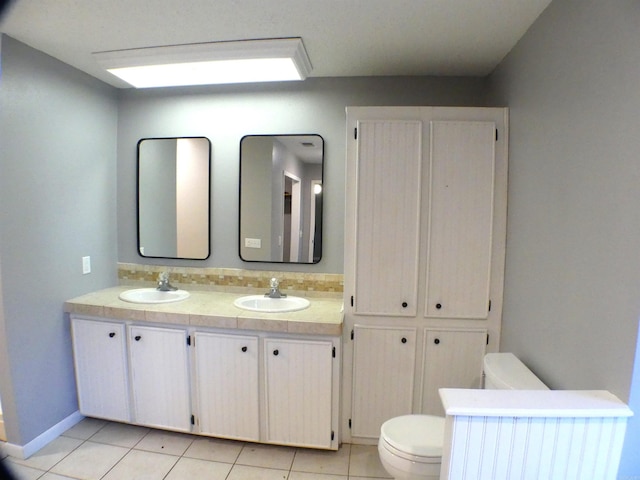 full bath with double vanity, a sink, toilet, and tile patterned floors