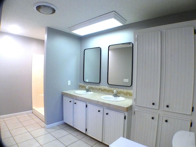 full bathroom with double vanity, tile patterned flooring, a sink, and baseboards