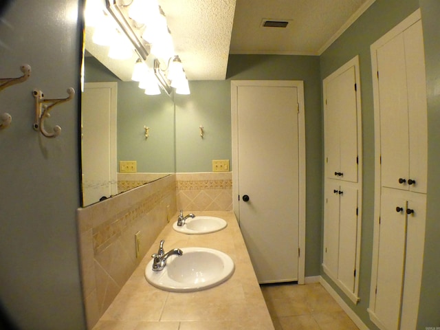 full bath featuring visible vents, a sink, a textured ceiling, and double vanity