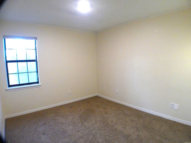 carpeted spare room featuring a textured ceiling and baseboards