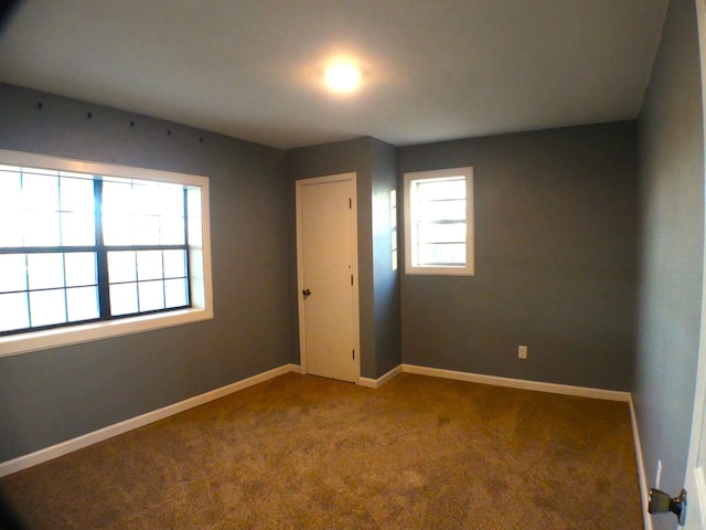 carpeted spare room featuring baseboards