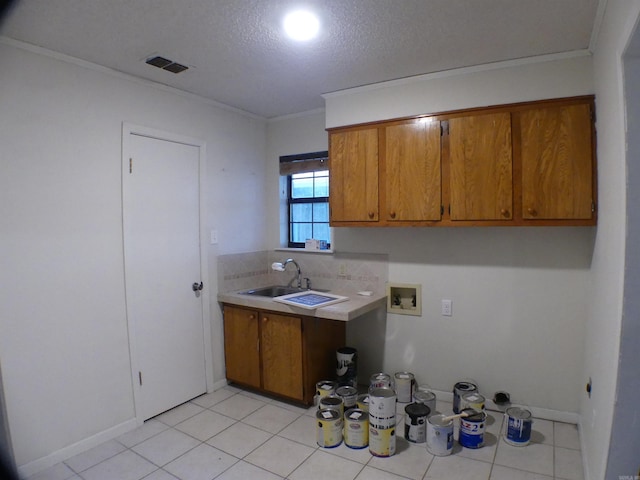 kitchen with a textured ceiling, a sink, light countertops, brown cabinets, and crown molding