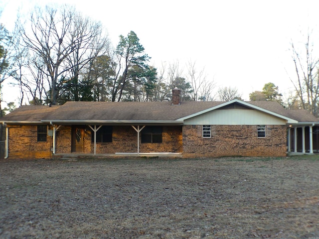 exterior space featuring brick siding, a chimney, and a shingled roof