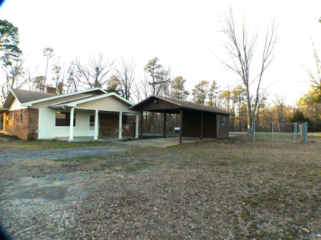 view of front of property with a carport, driveway, fence, and a chimney