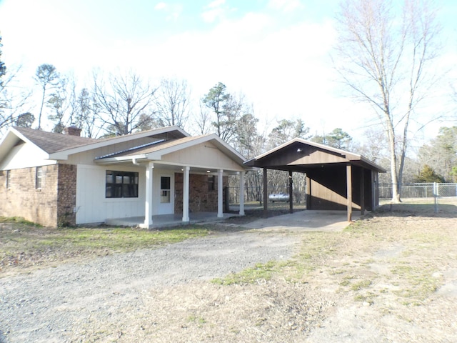 view of front of property featuring driveway, brick siding, and fence