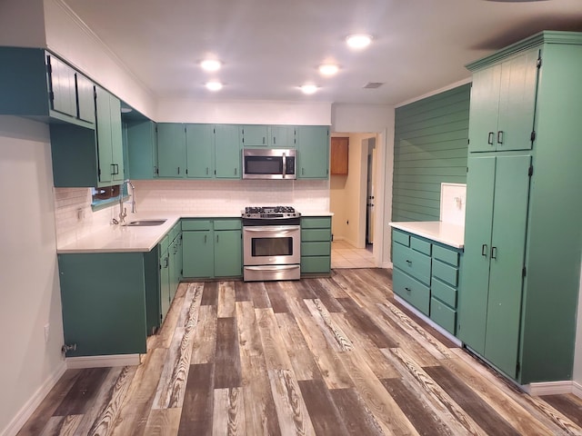 kitchen featuring tasteful backsplash, stainless steel appliances, a sink, and wood finished floors