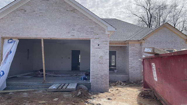 view of front of home featuring brick siding and roof with shingles