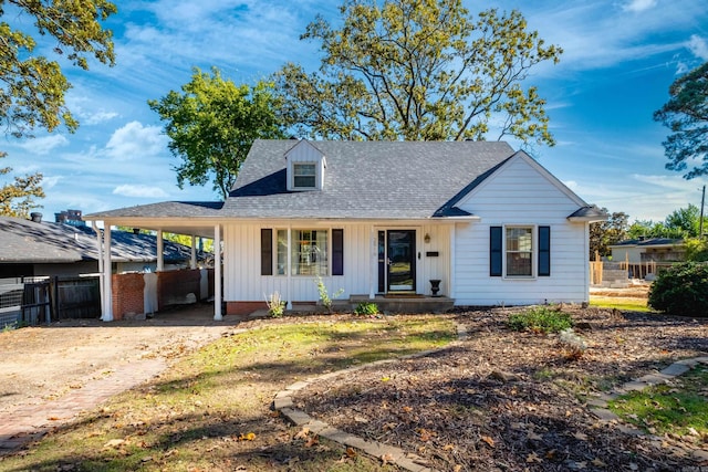 view of front of property featuring a carport, a shingled roof, fence, and board and batten siding