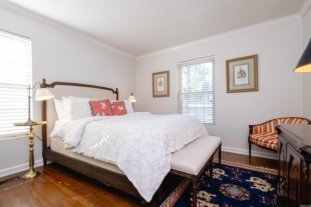 bedroom with ornamental molding, visible vents, baseboards, and wood finished floors