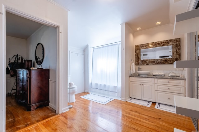 interior space with ornamental molding, vanity, toilet, and wood finished floors