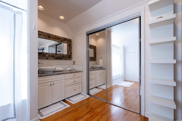 bathroom with vaulted ceiling, wood finished floors, vanity, and recessed lighting